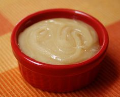 a red bowl filled with cream sitting on top of a table