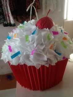 a red cupcake with white frosting and sprinkles sitting on top of a table