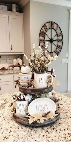 three tiered tray with coffee mugs and fall decorations on top of a kitchen counter