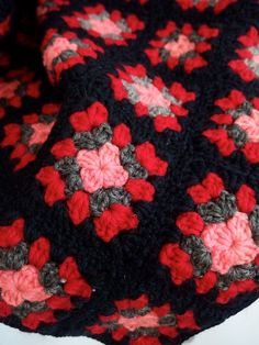 a black and red crocheted blanket with flowers on it