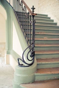 a set of stairs with wrought iron railings and handrail in an old building