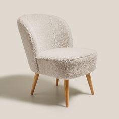 an upholstered chair with wooden legs and a white seat cover on the back