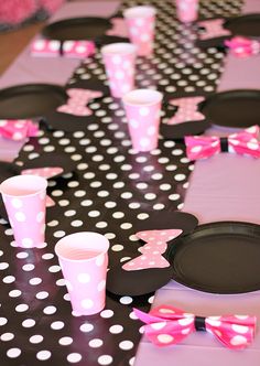 the table is decorated with pink and black polka dot paper plates, cups, and minnie mouse napkins