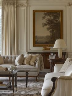 a living room filled with furniture and a painting hanging on the wall above it's windows