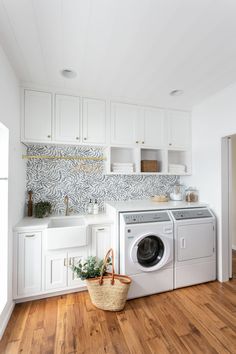 a washer and dryer in a white kitchen with wood flooring, cabinets and counter tops