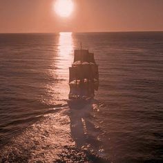 a ship sailing in the ocean at sunset