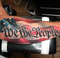 a man's arm with an american flag and we the people lettering on it