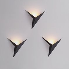 three lights are placed in the shape of an origami plane on a wall