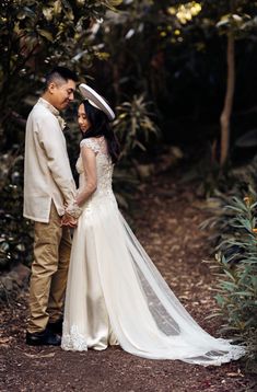 a bride and groom standing together in the woods looking at each other while holding hands