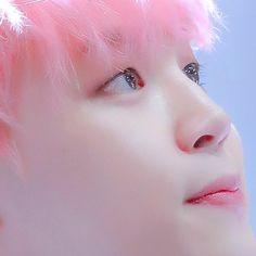 a close up of a person with pink hair and piercings on their ears, looking to the side