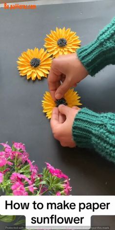 someone is making sunflowers out of paper and yarn with their hands on the table