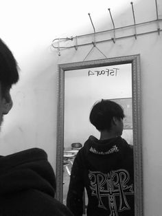 a man standing in front of a mirror looking at his own reflection on the wall