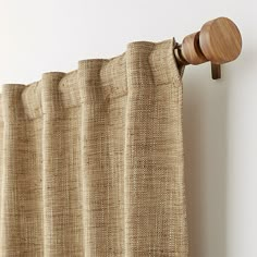 a curtain with a wooden rod hanging from it's side next to a white wall