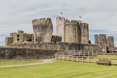 an old castle sits in the middle of a grassy field with two benches on it