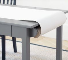 a close up of a table with a roll of paper on the top and two chairs behind it