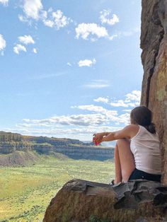 a woman sitting on top of a rock next to a cliff