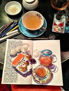 an open book sitting on top of a table next to a cup of tea and saucer