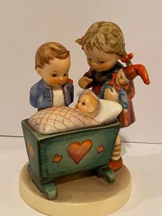 a figurine of two children with a baby in a bathtub and an infant