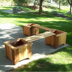 two wooden benches sitting on top of a cement ground next to grass and trees in the background