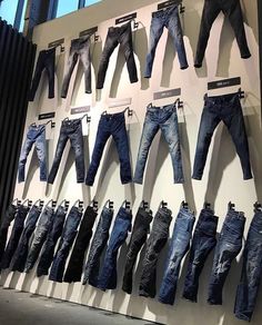 several pairs of jeans are displayed in front of a wall with images of men's pants