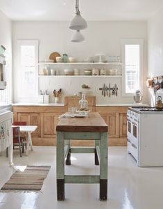 a kitchen with an island in the middle and lots of shelves on the wall above it