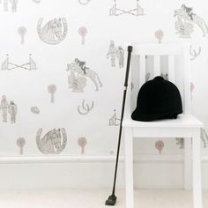 a black hat sitting on top of a white chair in front of a wallpaper