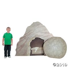 a young boy standing next to a rock with a bed in it