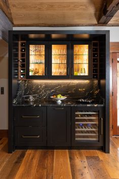 a kitchen with black cabinetry and marble counter tops, wood flooring and wooden ceiling