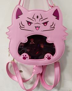 An itabag featuring everyone's favorite curse cat! This ita bag is made with pu leather as well as cotton insides for a sturdy exterior and a soft interior.  It comes with one main storage compartment as well as 4 internal pockets: one large padded pocket, two smaller open pockets, and one zipper pocket. Itabag Size: 9" x 9" x 3" (14" total with tail and ears) The ita bag includes:  - 1 Removable tail  - 1 Crossbody strap - 2 Backpack style straps - 1 Removable purple insert For extra inserts or Gojocat bag, please check out my other shop listings! Kawaii Style Large Capacity Standard Backpack, Kawaii Large Capacity Standard Backpack, Cat Design Crossbody Travel Bag, Pink Bags With Case For Daily Use, Kawaii Shoulder Bag With Cat Design For Daily Use, Kawaii Cat Design Shoulder Bag For Daily Use, Kawaii Tote Bag With Cat Design, Harajuku School Bag With Cat Design, Kawaii Cat Design Tote Bag