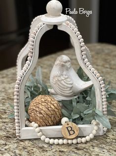 a bird figurine sitting on top of a table next to a pine cone