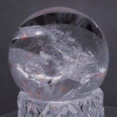 a crystal ball with ice on it sitting on top of a glass table next to a black background