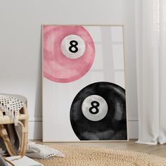 an art print with two pool balls on it in front of a white wall and wicker chair