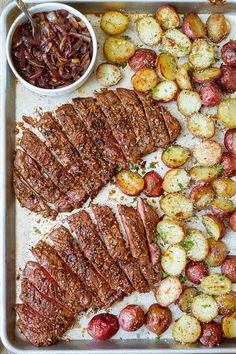 steak and potatoes on a baking sheet with dipping sauce