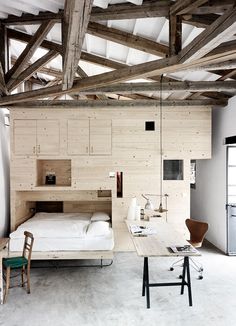 a bed sitting under a wooden beam in a bedroom next to a desk and chair