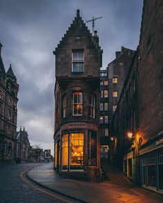 an old building on the corner of a city street at night with its lights on