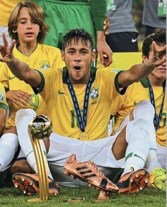 the soccer players are sitting on the ground with their trophies in front of each other