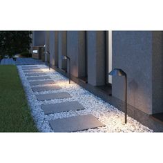 modern outdoor lighting on the side of a building at night with grass and stones in front