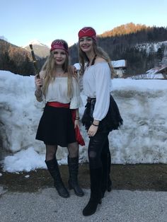 two young women dressed in pirate costumes posing for the camera with snow on the ground behind them