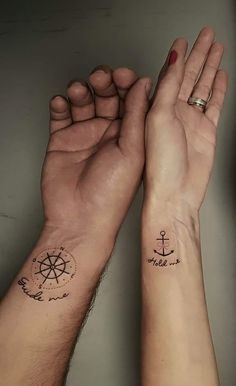 two people holding hands with tattoos on their wrists and wristbands, one has an anchor and the other has a compass