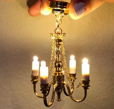 a chandelier with five lit candles hanging from it's arms and hands