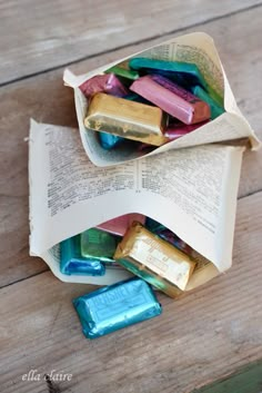 an open book with candy bars in it on a wooden table next to a pile of books