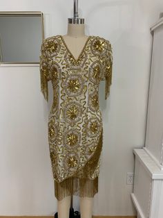 "very delicate and beautiful vintage silk cocktail dress Gold sequin and beads Shoulder pad V neck Back hook and zipper Fully lined Hand made in India size: vintage M/fits small to medium measurements; shoulder to shoulder-17\" bust-36\" arm length-5\" arm pit to arm pit-17.5\" waist-from 32\" hip-18\"(for all the way around double the measurement) total length-36\" tassel 5\" color: cream/gold condition: excellent, missing minimal sequin pieces" Champagne Sequin Dress For Celebration, Elegant Embellished Sequin Dress For Celebration, Gold Silk Dress With Sequins, Elegant Gold Flapper Dress For Evening, Elegant Gold Flapper Dress For Festive Occasions, Elegant Fitted Sequin Dress For Celebration, Party Silk Sequin Embellished Dress, Vintage Sequined Flapper Dress For Formal Occasions, Gatsby Style Embellished Sequin Cocktail Dress