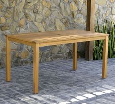 a wooden table sitting in front of a stone wall