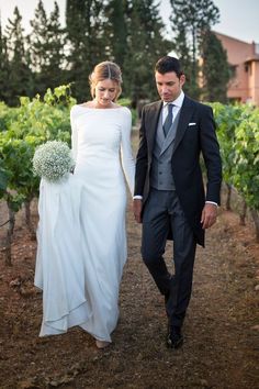 a bride and groom walking through the vineyard