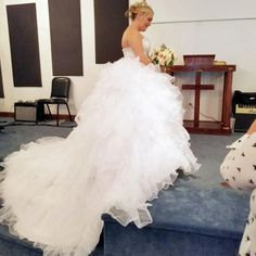 a woman in a white wedding dress is walking down the stairs