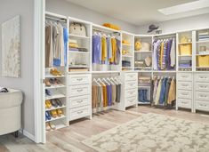 an organized walk in closet with white cabinets and drawers