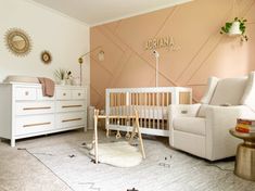 a baby's room with a crib, chair, dresser and mirror on the wall