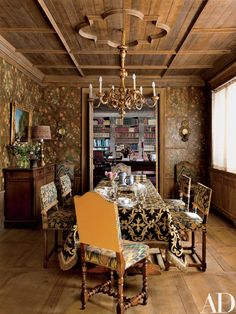 a dining room with a chandelier, table and chairs next to a bookshelf