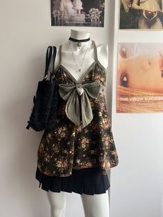 a mannequin wearing a dress with a bow on the neck and purse in front