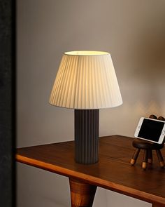 a lamp sitting on top of a wooden table next to a cell phone